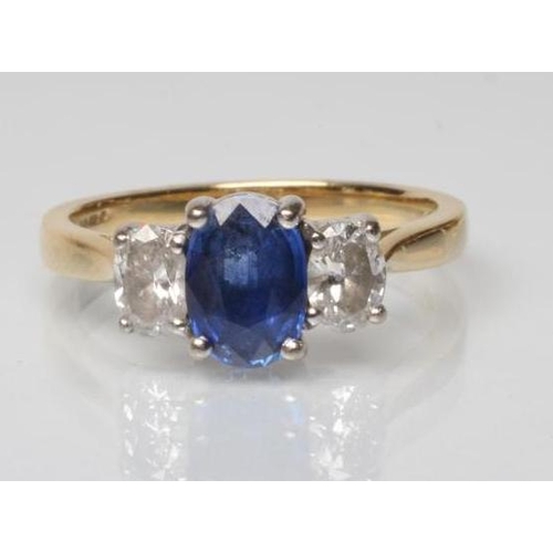 207 - A SAPPHIRE AND DIAMOND THREE STONE RING, the central oval facet cut sapphire claw set and flanked by... 