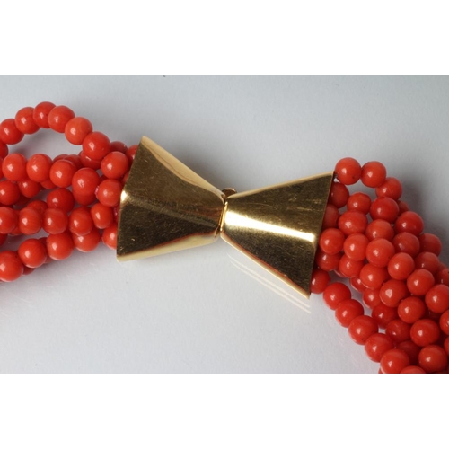 215 - AN EIGHT STRAND CORAL BEAD NECKLACE on unmarked gold bow clasp, 32