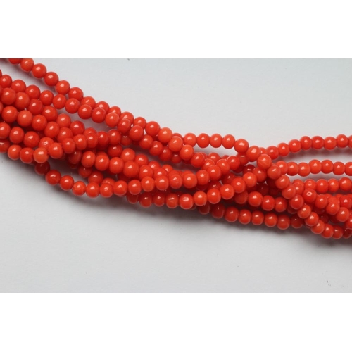 215 - AN EIGHT STRAND CORAL BEAD NECKLACE on unmarked gold bow clasp, 32