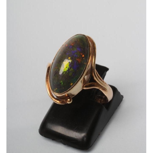 216 - AN OPAL RING, the oval cabochon polished green stone in an art nouveau style rub-over setting to a p... 