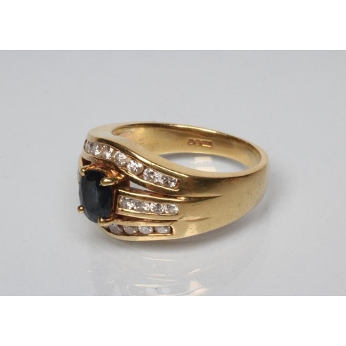 249 - A SAPPHIRE AND DIAMOND DRESS RING, the oval facet cut sapphire claw set to an open triple panel chan... 