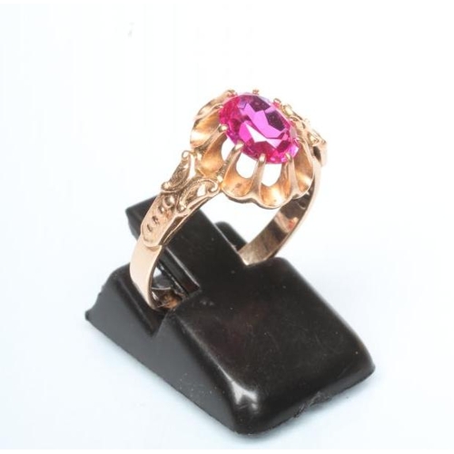 251 - A RUBY COCKTAIL RING, the oval facet cut stone claw set to a frilled mount and cast shoulders to a p... 