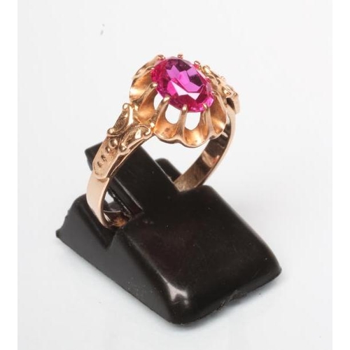 251 - A RUBY COCKTAIL RING, the oval facet cut stone claw set to a frilled mount and cast shoulders to a p... 