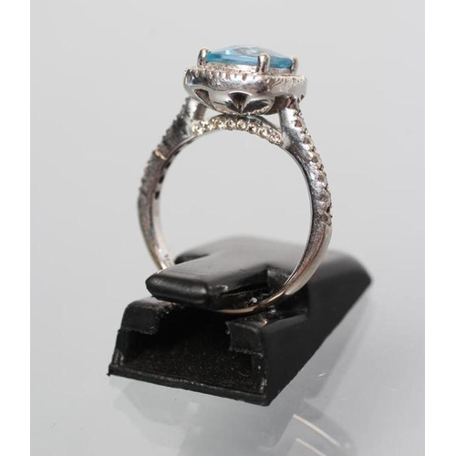 259 - A DRESS RING, the cushion cut blue topaz point set to a border of numerous small diamonds to similar... 