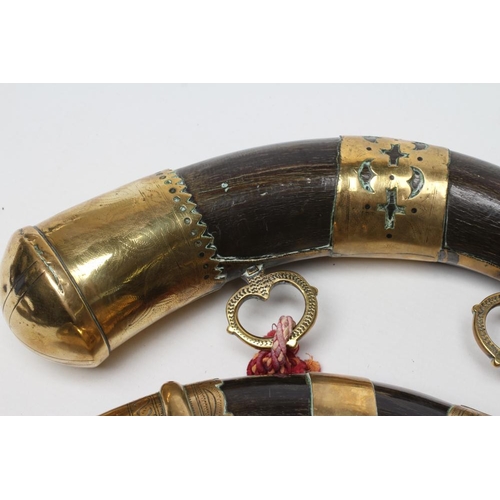 326 - A MATCHED PAIR OF BRASS MOUNTED HORN POWDER FLASKS both with highly decorated metal work and twin ha... 