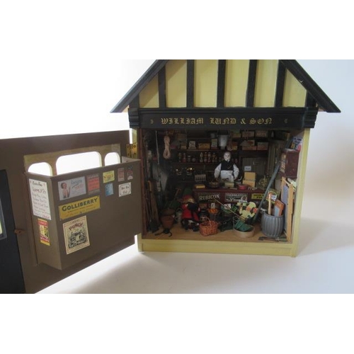 113 - A doll's house village shop, of painted wood construction, with well filled display window, external... 