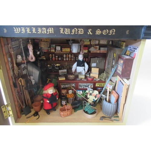 113 - A doll's house village shop, of painted wood construction, with well filled display window, external... 