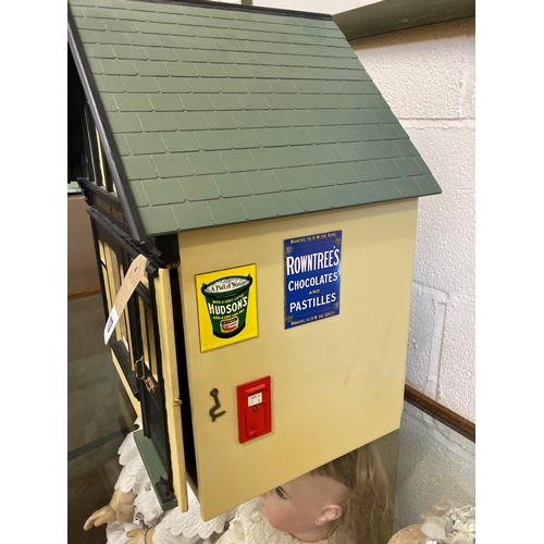 113 - A doll's house village shop, of painted wood construction, with well filled display window, external... 