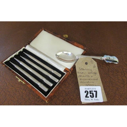 257 - CASED SET OF FOUR STERLING SILVER BRIDGE PENCILS AND AN ENAMELLED SOUVENIR SPOON