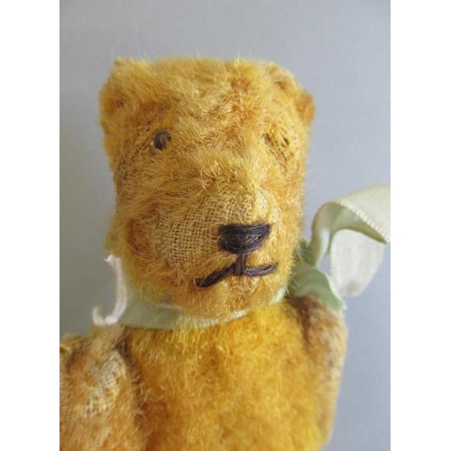 120 - A miniature straw filled teddy, with one amber eye, sewn nose, hinged joints and orange plush, 5 7/8... 