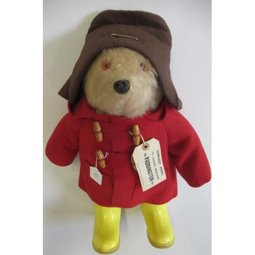 141 - A Paddington bear, with amber eyes, plastic nose, felt red coat, yellow Dunlop boots, Brown hat and ... 