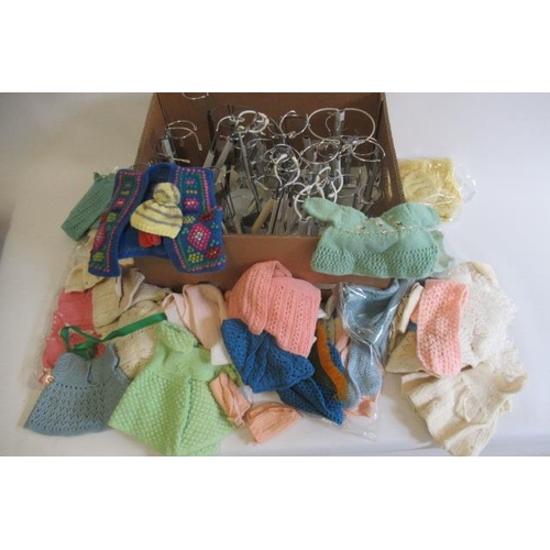 23 - A quantity of mainly woollen dolls clothing, together with a box of doll stands