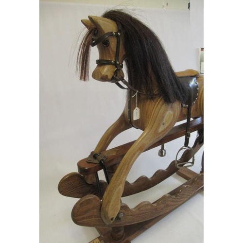 283 - An Ian Armstrong rocking horse of carved laminate form, with amber eyes, leather saddle and harness,... 