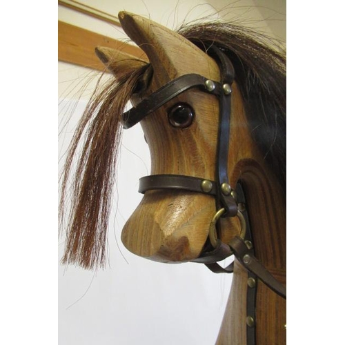 283 - An Ian Armstrong rocking horse of carved laminate form, with amber eyes, leather saddle and harness,... 