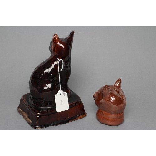 20 - AN ENGLISH TREACLE GLAZED STONEWARE CAT, early 19th century, modelled seated on an oblong base, 7 1/... 