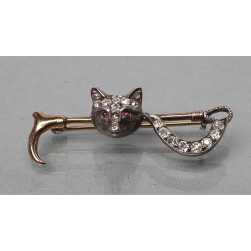 376 - AN EDWARDIAN STOCK PIN, the crop centred by a fox mask with ruby cabochon eyes and diamond set head ... 