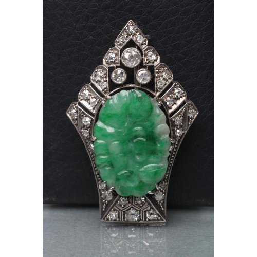 379 - AN ART DECO JADE AND DIAMOND BROOCH, the oval green jade panel carved with fruits and claw set to a ... 