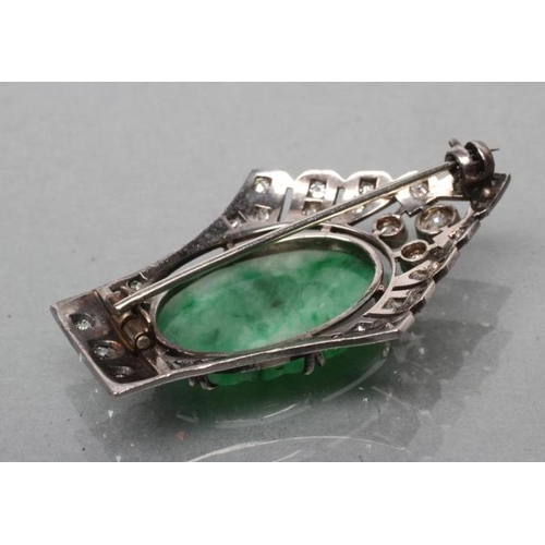 379 - AN ART DECO JADE AND DIAMOND BROOCH, the oval green jade panel carved with fruits and claw set to a ... 