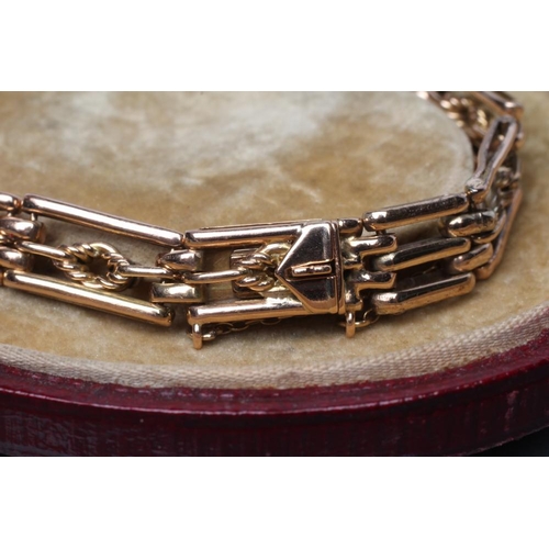 389 - AN EDWARDIAN GATE BRACELET, the ten open oblong links and clasp each centred by a rope twist lozenge... 