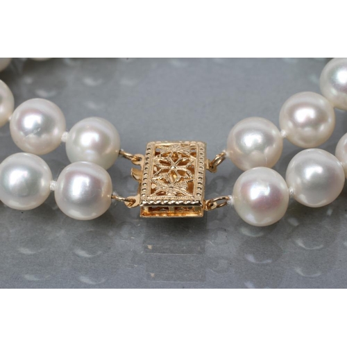 396 - A TWO ROW CULTURED PEARL BRACELET with two fixed spacers between and foliate pierced clasp, stamped ... 