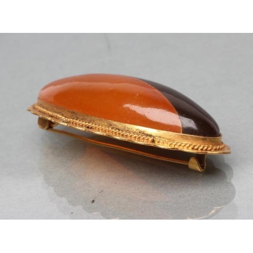 400 - AN AMBER BROOCH, the eliptical bi-colour panel open back set to an engraved mount, stamped RK9, 5cm ... 