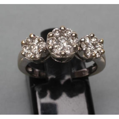 408 - A DIAMOND TRIPLE CLUSTER RING, the central seven stone cluster point set and flanked by a pair of si... 