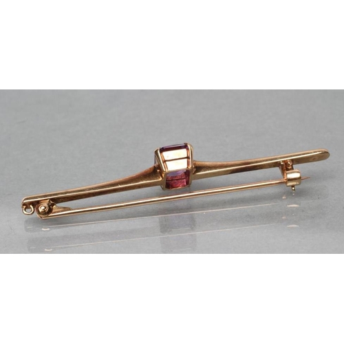 425 - AN EDWARDIAN PROPELLOR BAR BROOCH centred by an oblong facet cut amethyst, stamped 9ct (Est. plus 21... 