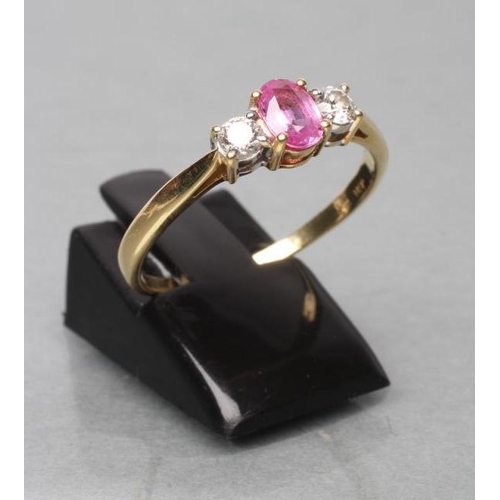 429 - A PINK SAPPHIRE AND DIAMOND THREE STONE RING, the oval facet cut sapphire claw set and flanked by tw... 