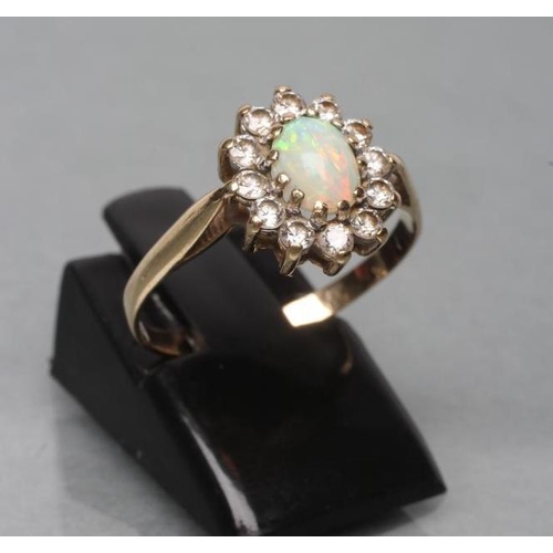 457 - AN OPAL AND DIAMOND CLUSTER RING, the oval cabochon polished opal claw set to a border of small roun... 