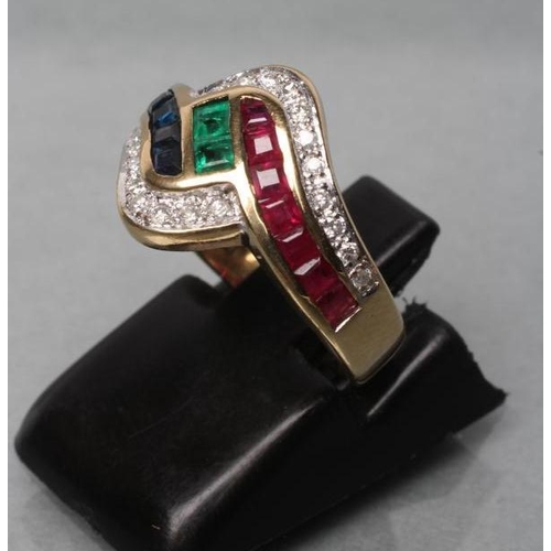 478 - A RUBY, SAPPHIRE AND EMERALD DRESS RING. the channel set calibre cut stones within point set diamond... 