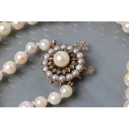 481 - A SINGLE STRING OF CULTURED PEARLS, with split pearl and emerald chip 9ct gold flower clasp, London ... 