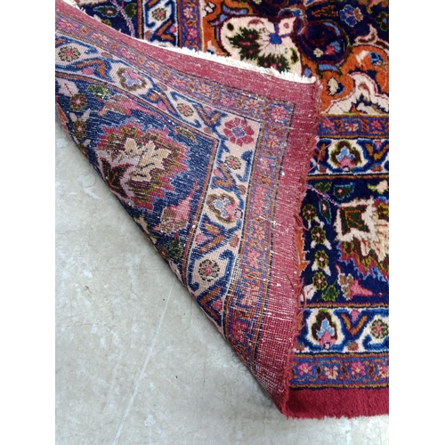 492 - A PERSIAN CARPET, the claret field with floral sprays with navy and tangerine central gul and matchi... 