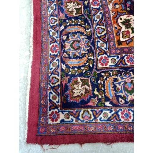 492 - A PERSIAN CARPET, the claret field with floral sprays with navy and tangerine central gul and matchi... 