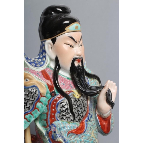 20 - A CHINESE PORCELAIN FIGURE modelled as a celestial warrior wearing brightly coloured robes holding a... 