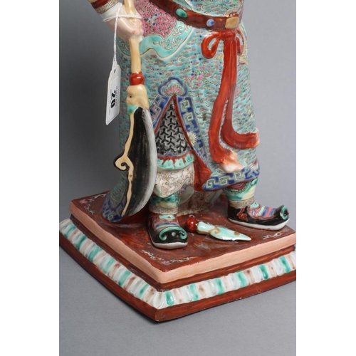 20 - A CHINESE PORCELAIN FIGURE modelled as a celestial warrior wearing brightly coloured robes holding a... 