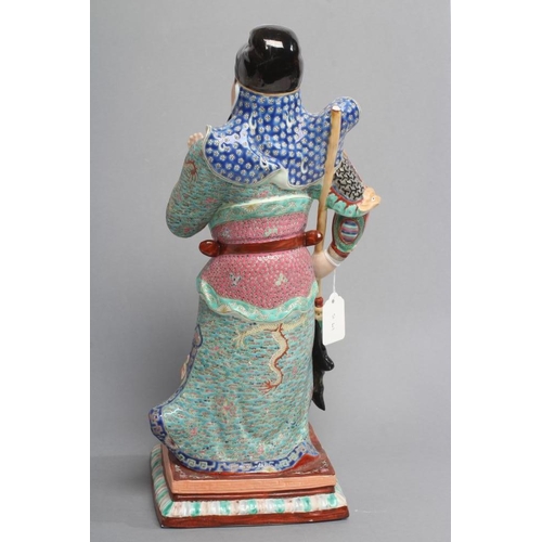 20 - A CHINESE PORCELAIN FIGURE modelled as a celestial warrior wearing brightly coloured robes holding a... 