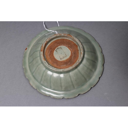 23 - A CHINESE CELADON GLAZED SMALL DISH of lobed circular form, centrally carved with a flower spray, 5 ... 