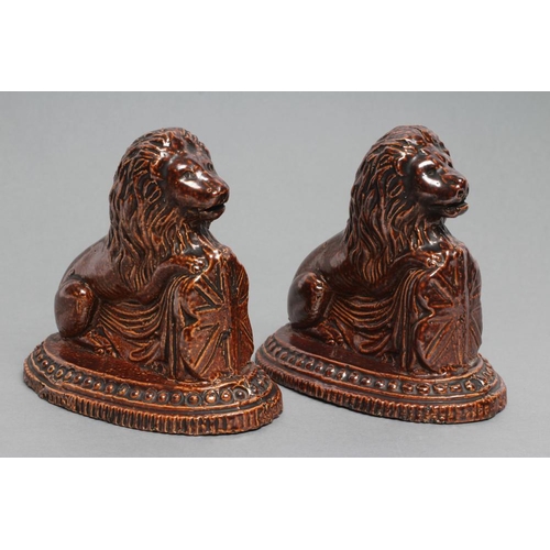 33 - A PAIR OF BRAMPTON TYPE BROWN SALTGLAZE STONEWARE LIONS, early 19th century, modelled resting their ... 