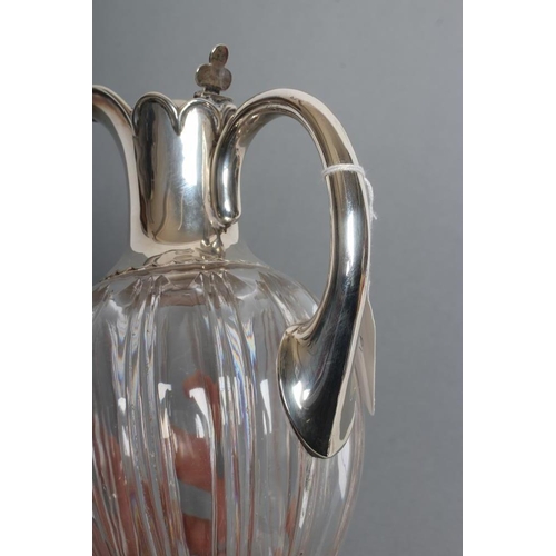 135 - AN EDWARDIAN SILVER MOUNTED CLEAR GLASS CLARET JUG, maker John Grinsell & Sons, Birmingham 1903, the... 