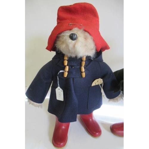 211 - Two Paddington Bears, both in red Dunlop boots and red hats, one in a blue coat and one in green, on... 