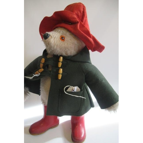 211 - Two Paddington Bears, both in red Dunlop boots and red hats, one in a blue coat and one in green, on... 