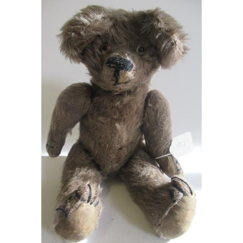 213 - An old teddy bear, with light brown plush, glass eyes, sewn nose, large ears, hump and fabric pads, ... 