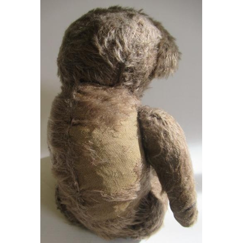 213 - An old teddy bear, with light brown plush, glass eyes, sewn nose, large ears, hump and fabric pads, ... 