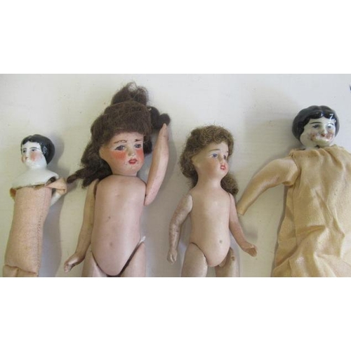 52 - Four antique dolls, comprising two china shoulder head dolls, with cloth bodies and bisque lower arm... 