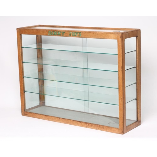 611 - A glass toy shop display cabinet, wooden frame with four glass shelves, DINKY TOYS to front, 32