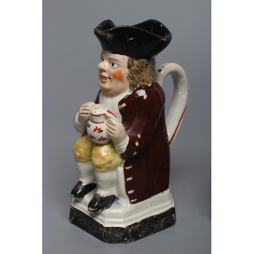 24 - A PEARLWARE SMALL TOBY JUG, c.1800, wearing a tricorn hat, red coat, pink waistcoat and yellow breec... 