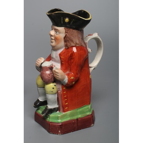 24 - A PEARLWARE SMALL TOBY JUG, c.1800, wearing a tricorn hat, red coat, pink waistcoat and yellow breec... 