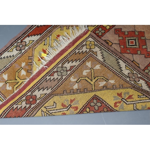 291 - A KAZAK TYPE RUG, the oblong field with central rust coloured gul and similar border, on a bold yell... 