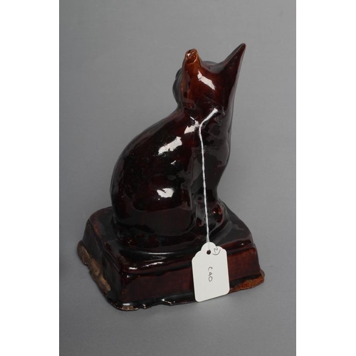 33 - AN ENGLISH TREACLE GLAZED STONEWARE CAT, early 19th century, modelled seated on an oblong base, 7 1/... 