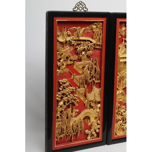 312 - A PAIR OF CHINESE CARVED WOOD WALL PANELS, 20th century, gilded with garden scenes in high relief on... 